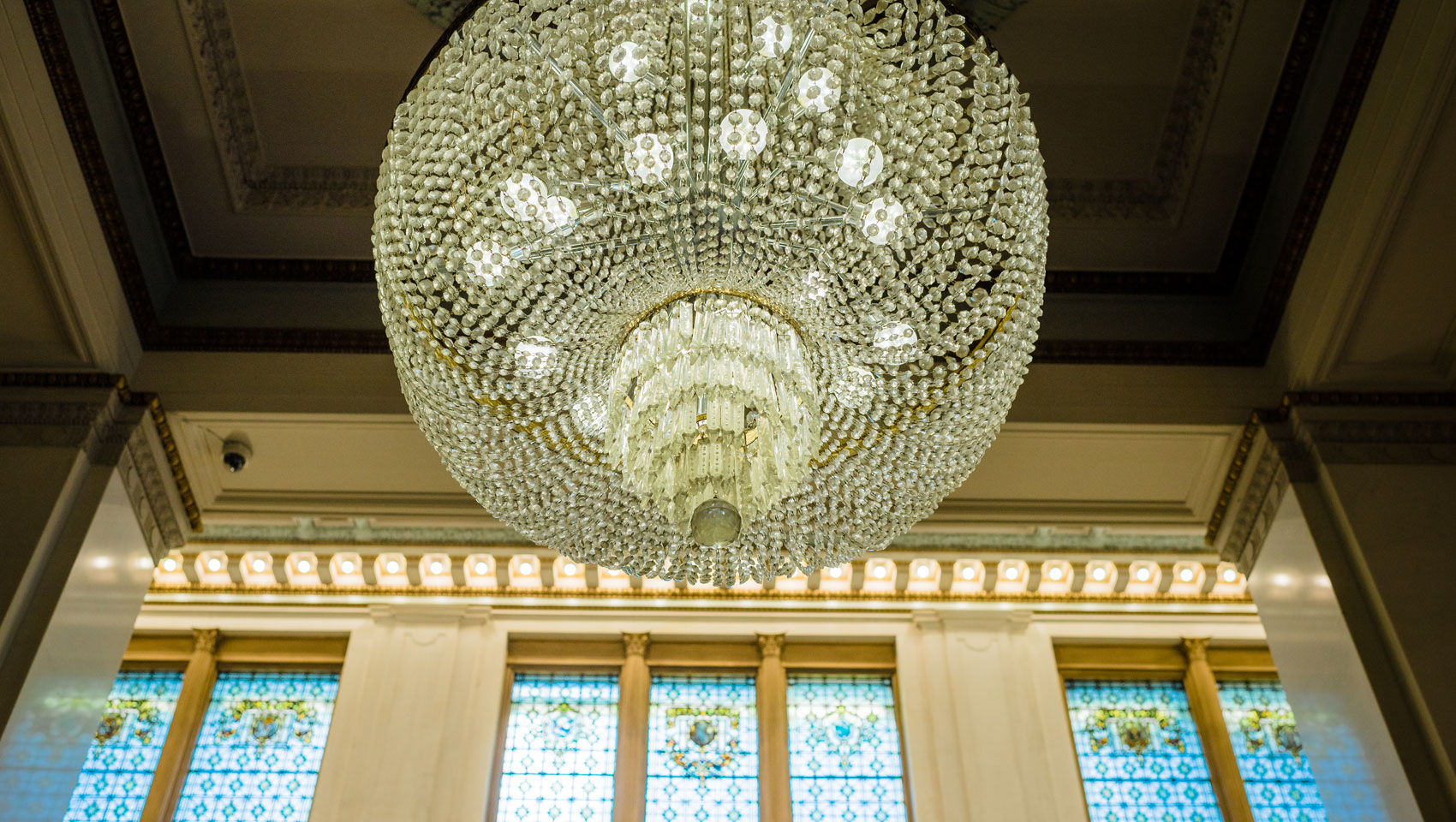 Upward view of the main entryway's grandiose chandelier that illuminates the open space's marble surroundings.
